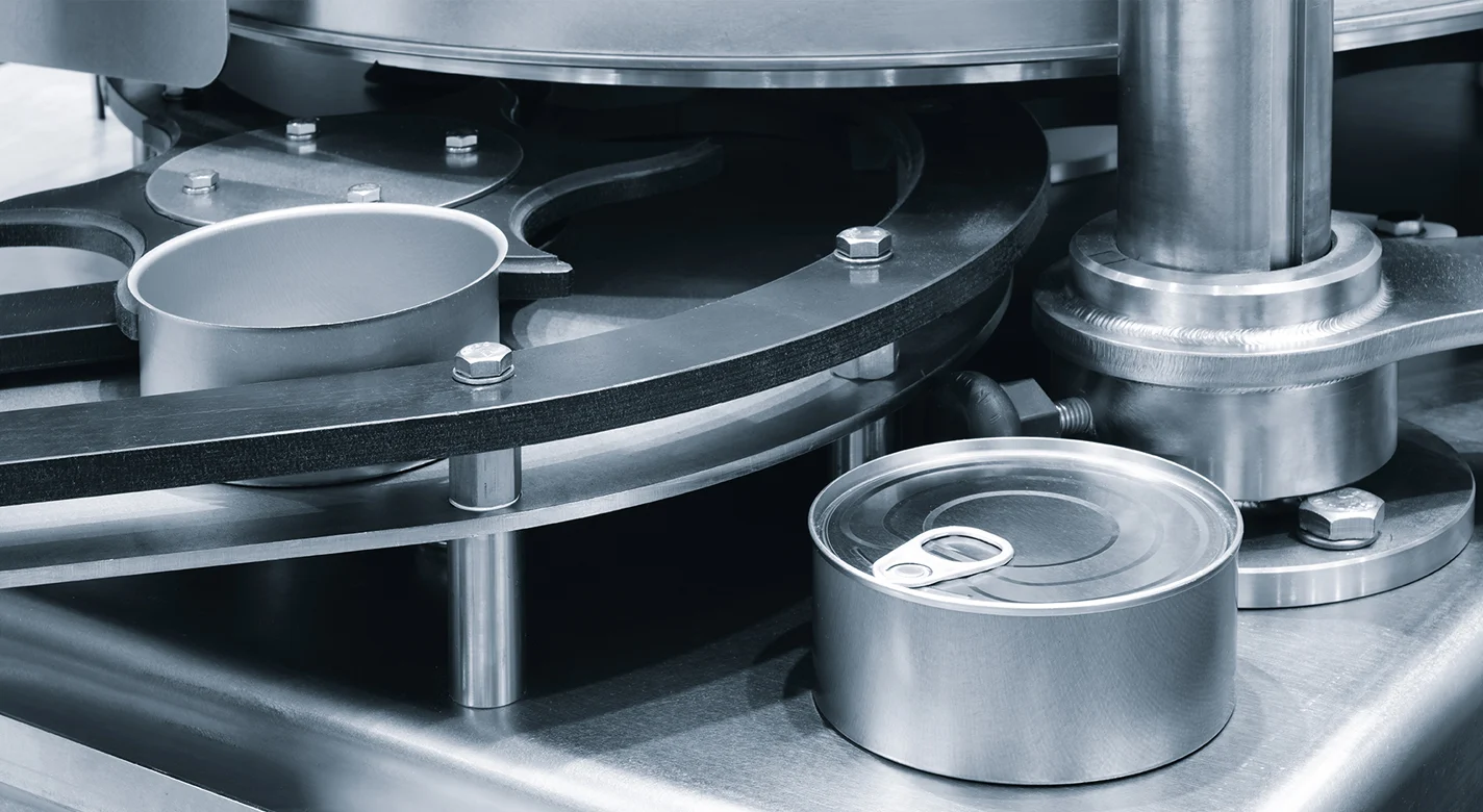 Máquina industrial de processamento de latas, com uma lata aberta e outra selada com argola