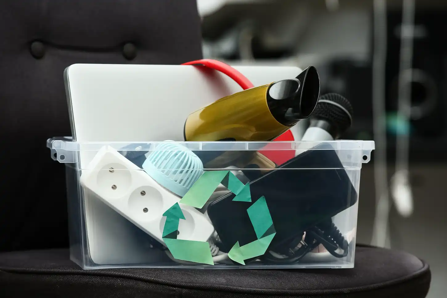 Caixa transparente com resíduos eletrónicos e símbolo de reciclagem
